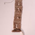 Rectangular fibrous sheet embrodiered with shell rings around the edges and in a square pattern.